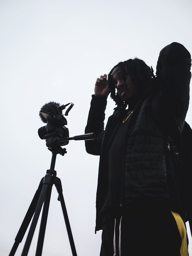 A photographer adjusting his camera on a tripod during daylight outdoors.