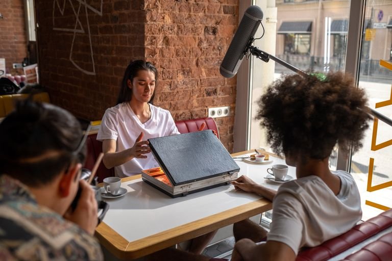 Casual film scene with three people in a cafe, recording with boom mic.